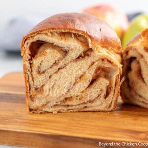 A loaf of Apple Cinnamon Babka cut in half and sitting on a wooden board.