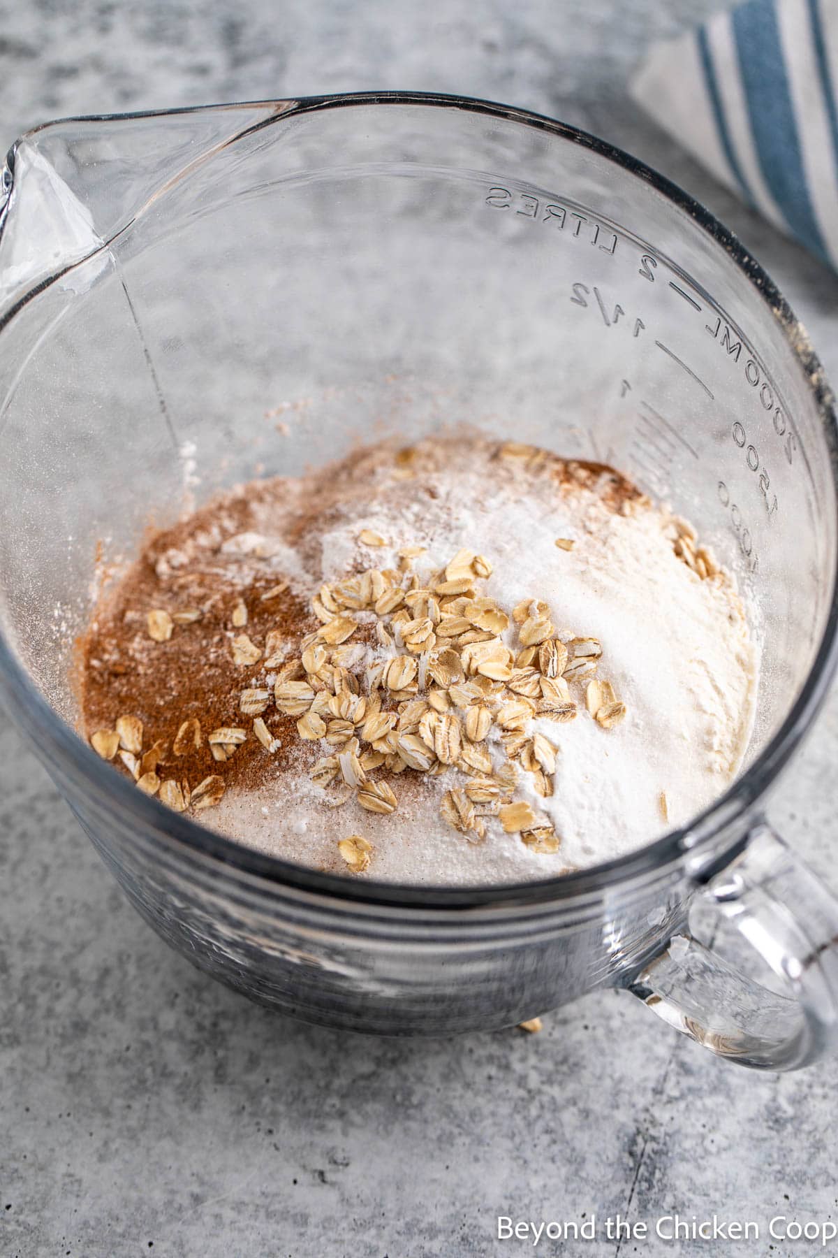 Mixing flour, oats, sugar and spices together in a glass bowl. 