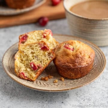Cranberry Banana Muffins on a small plate next to a cup of coffee.