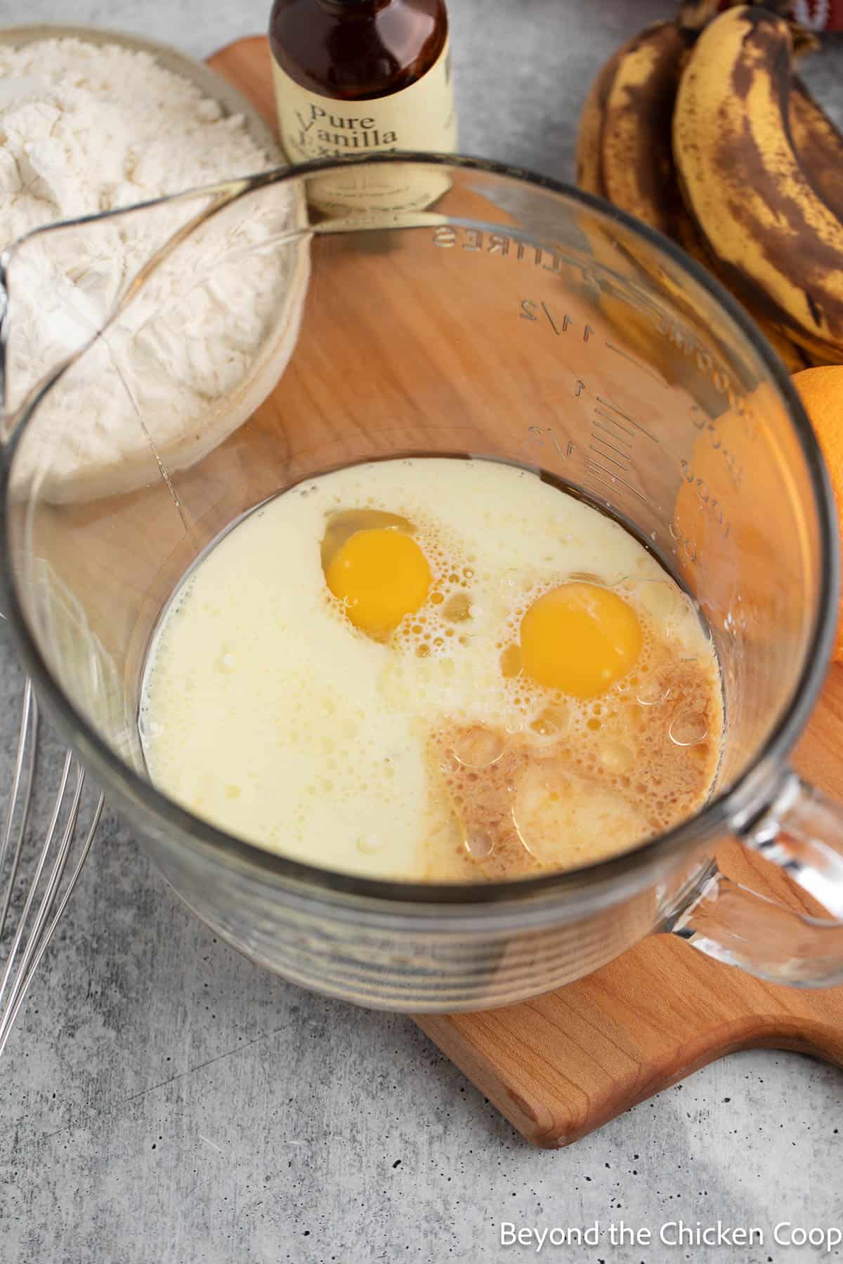 Eggs, milk, sugar and vanilla in a glass mixing bowl. 