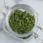 A small jar filled with dried oregano.