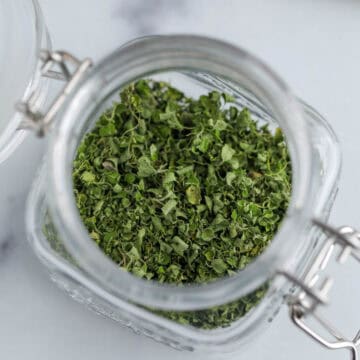 A small jar filled with dried oregano.
