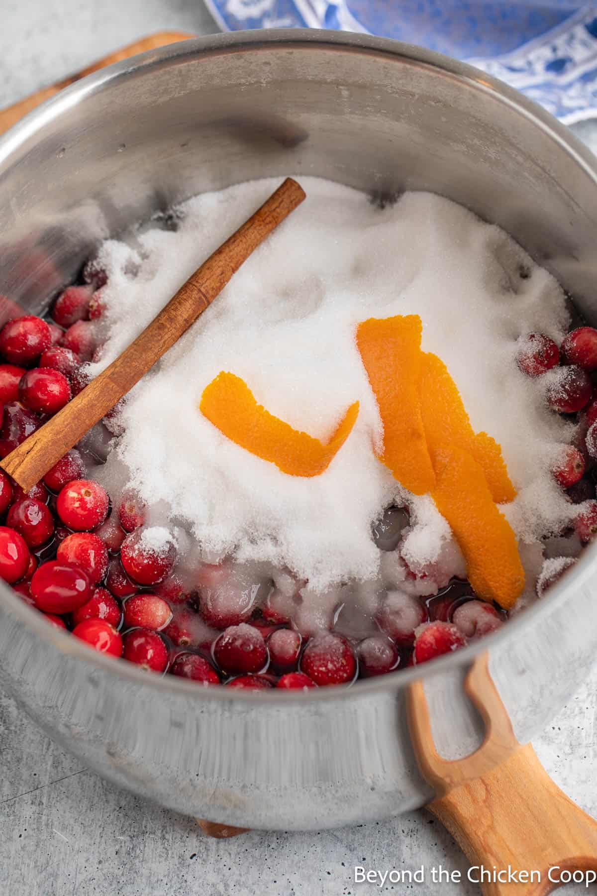 Cranberries, sugar, orange peel and a cinnamon stick in a large pot. 