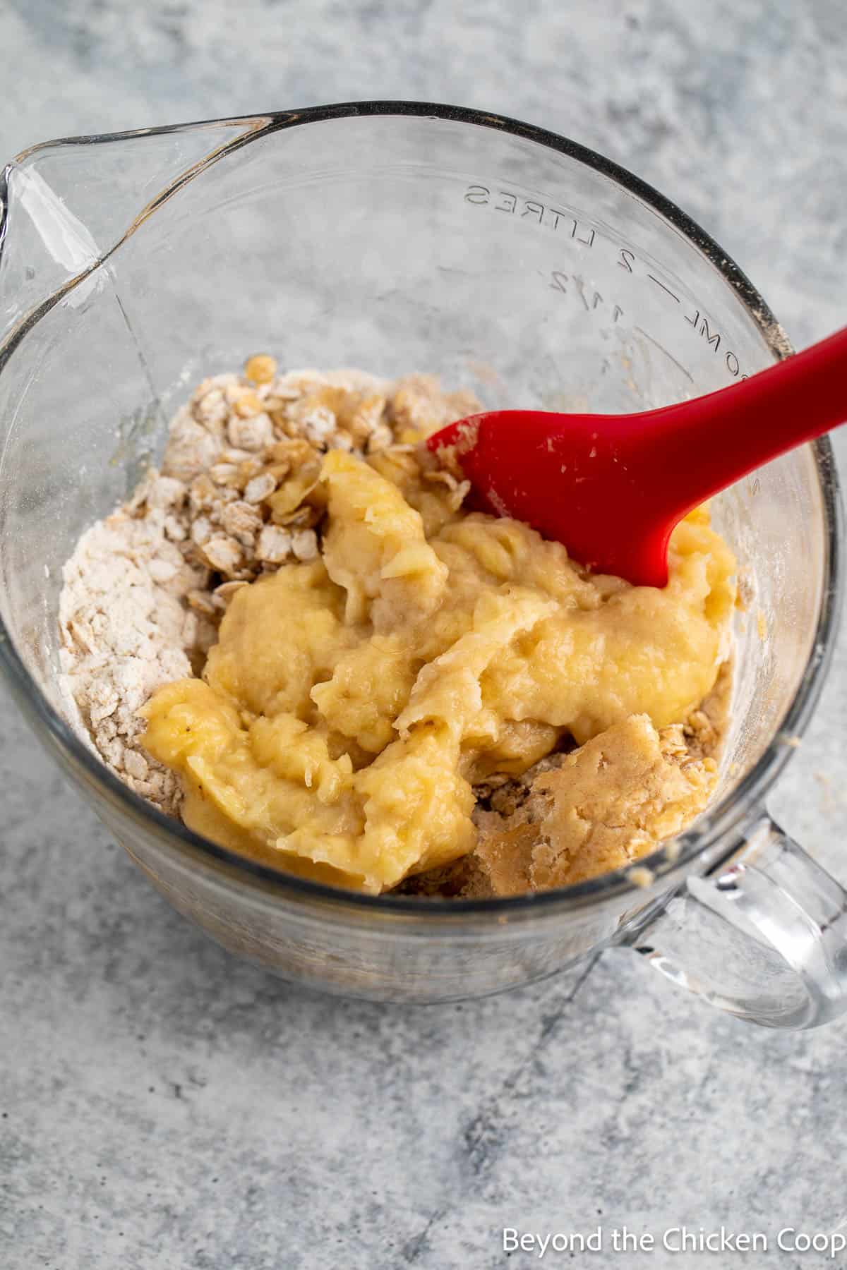Mashed bananas being stirred into muffin batter. 