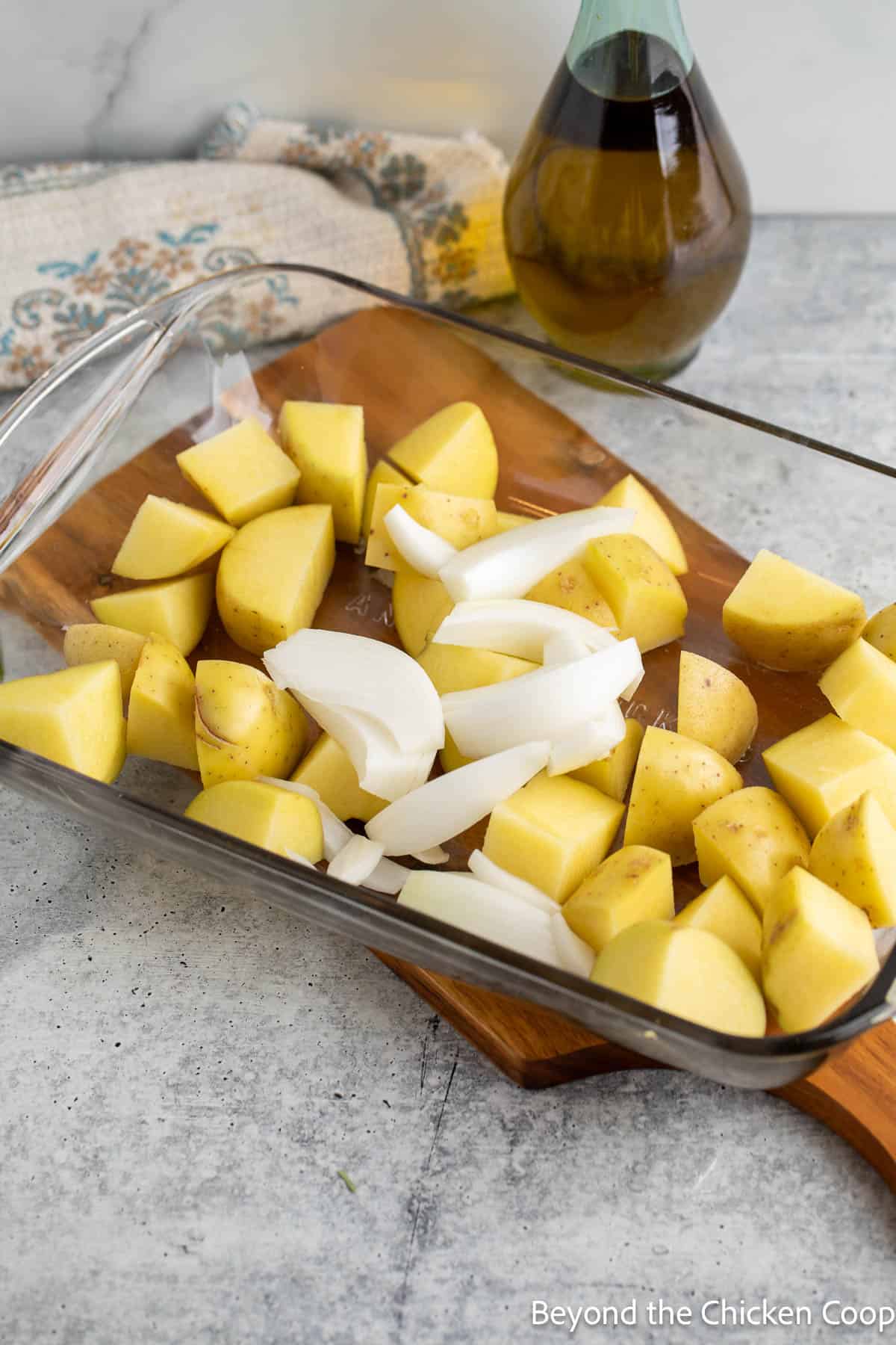 Cubed potatoes and sliced onions in a baking dish. 