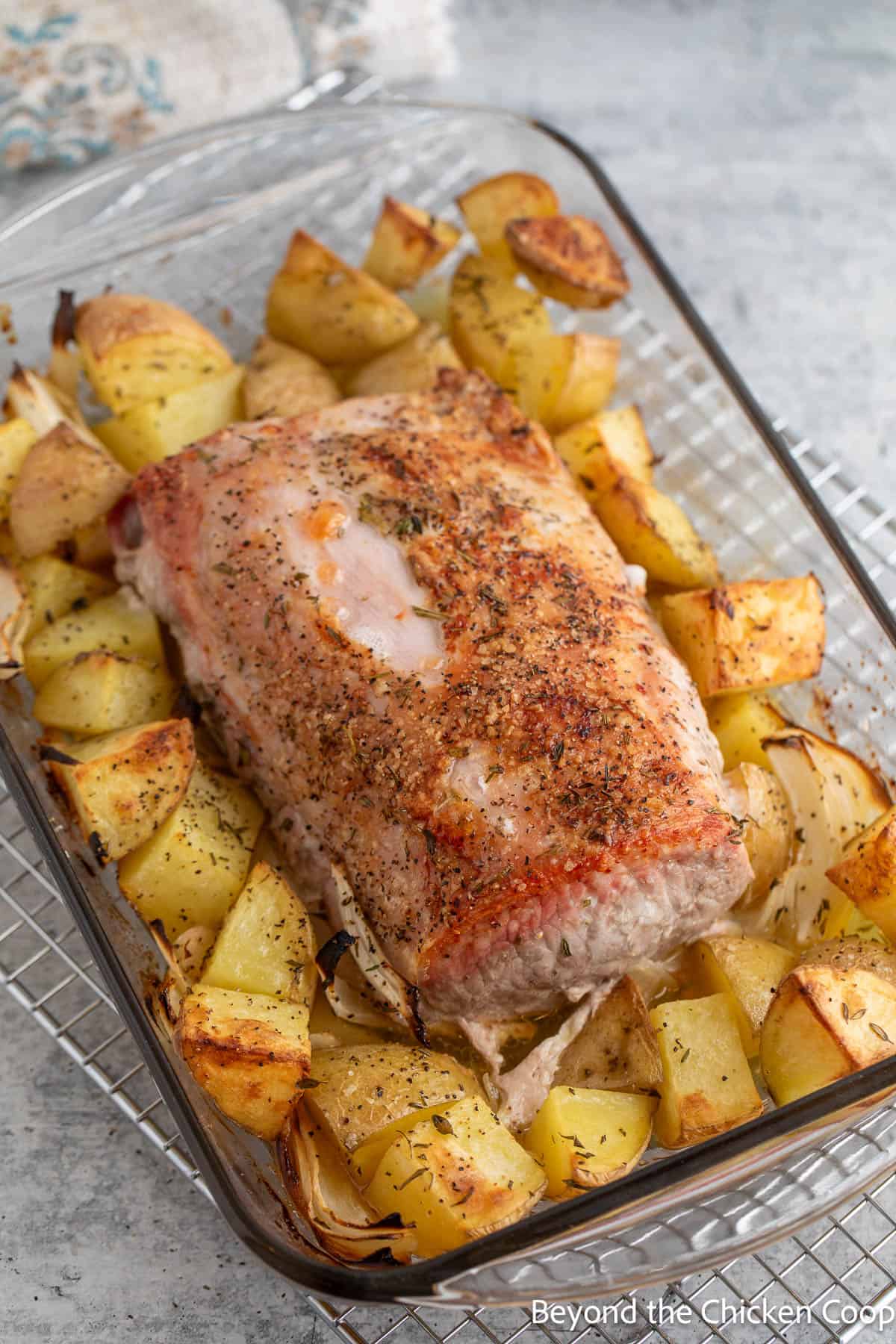 Baked pork loin with potatoes and onions in a glass casserole dish. 