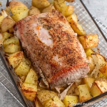 Roasted pork loin and potatoes in a baking dish.