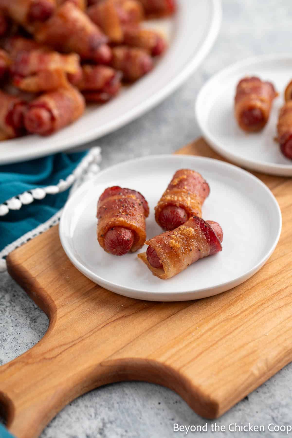 Little smokies wrapped in bacon on a small white plate. 