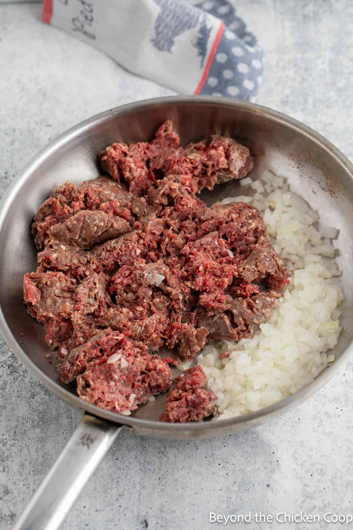 Cooking burger with onions in a large skillet. 