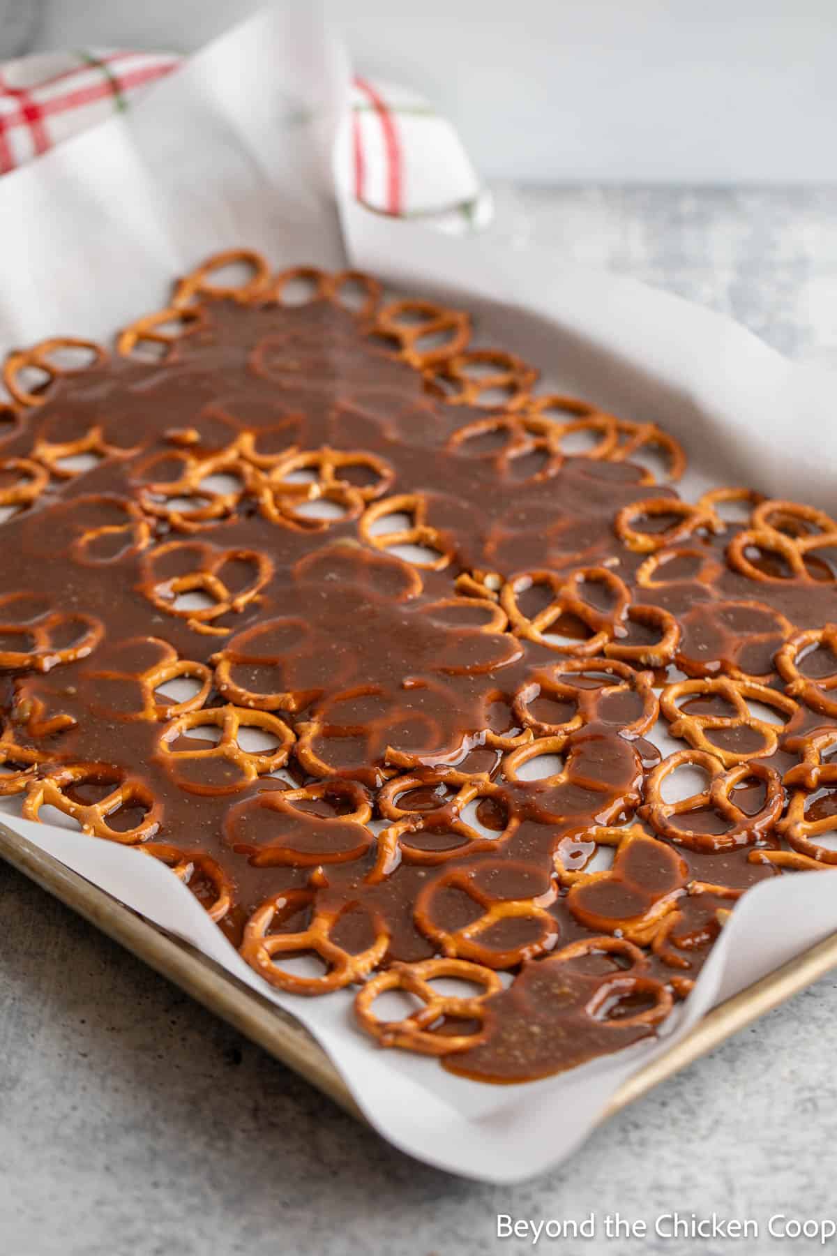 Caramel over pretzels on a baking sheet. 