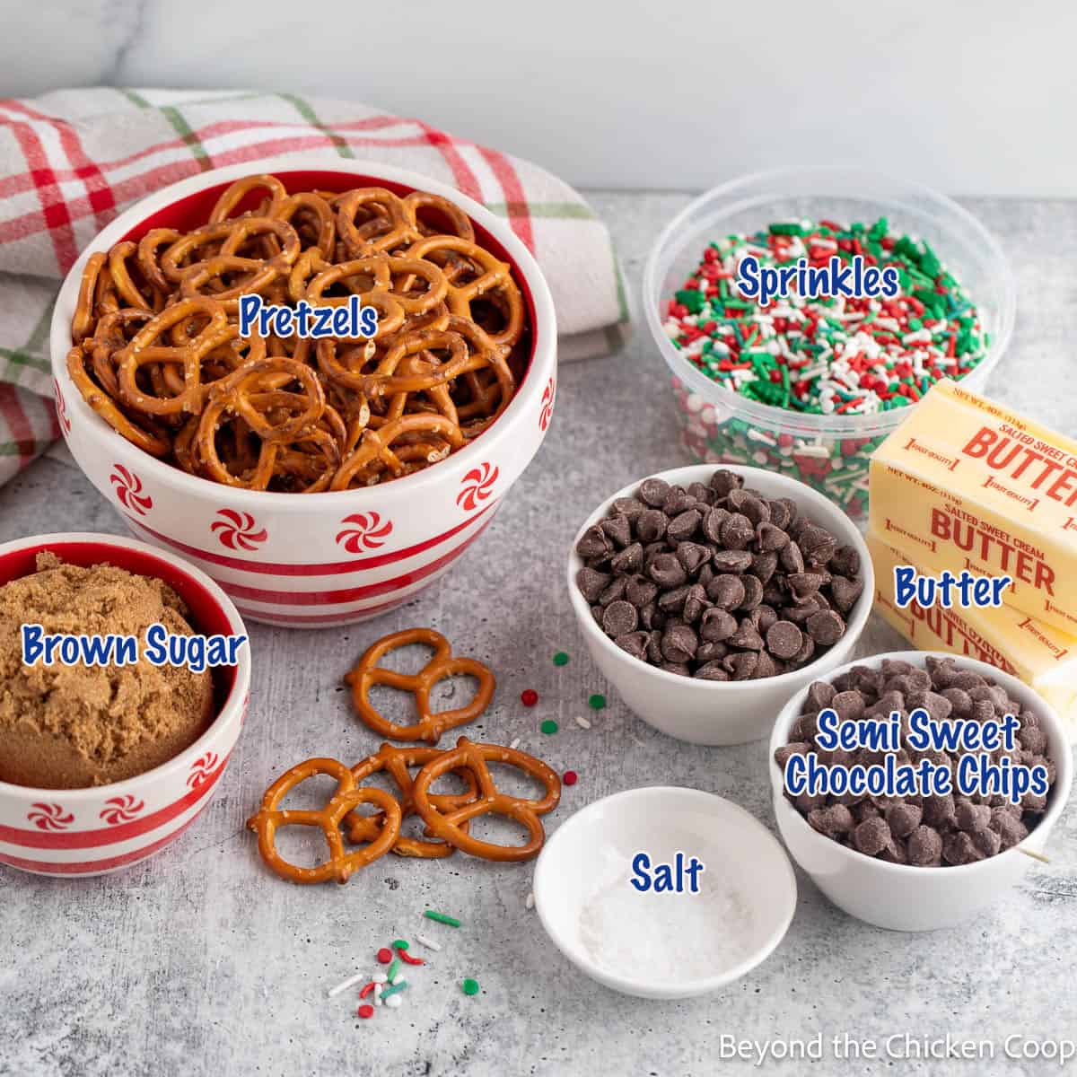 Ingredients in small bowls filled with pretzels, chocolate chips and brown sugar. 