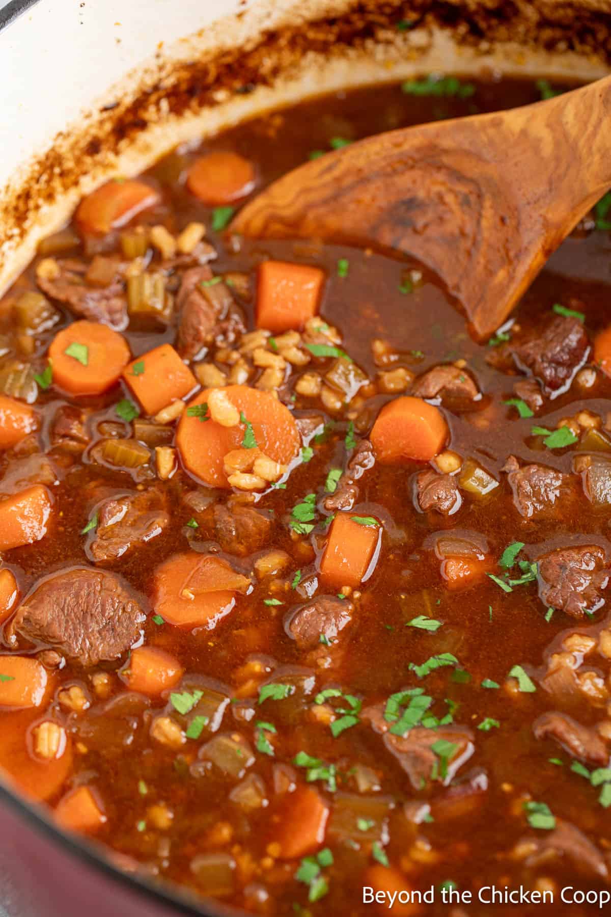 Beef Barley Soup in a pot with a wooden spoon. 