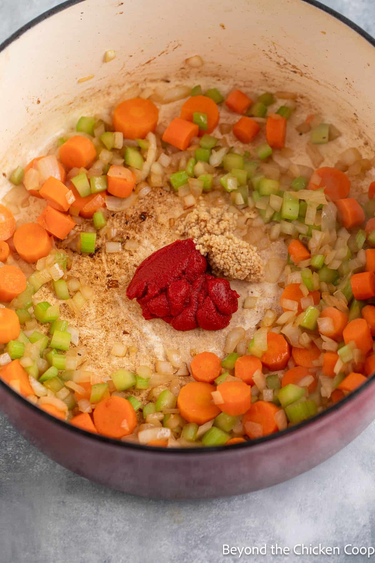 Adding tomato sauce to veggies in a pot. 