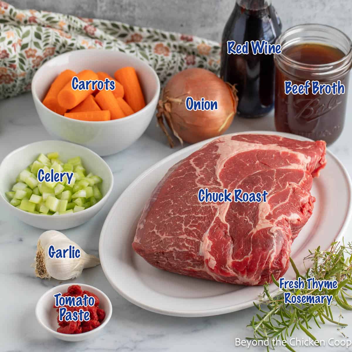 A raw chuck roast along with onions, celery and carrots and fresh herbs. 