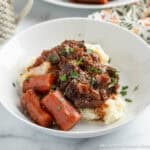 Braised chuck roast with carrots and gravy over mashed potatoes.