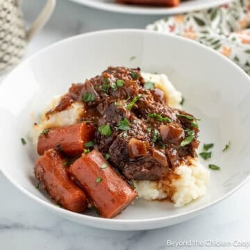 Braised chuck roast with carrots and gravy over mashed potatoes.