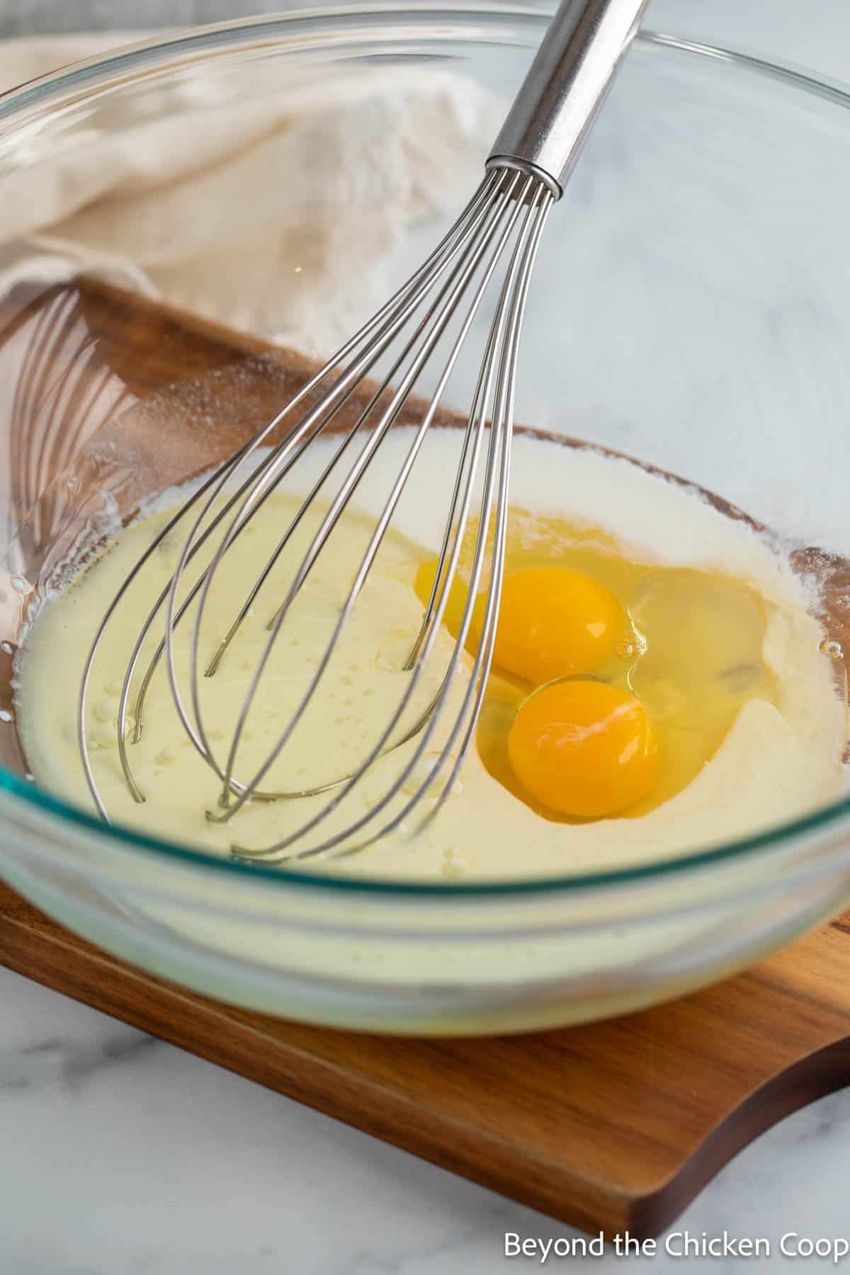 Eggs, oil and buttermilk in a glass bowl with a whisk. 