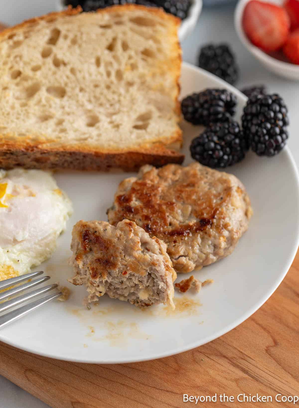 Breakfast sausage on a plate with an egg, toast, and berries. 