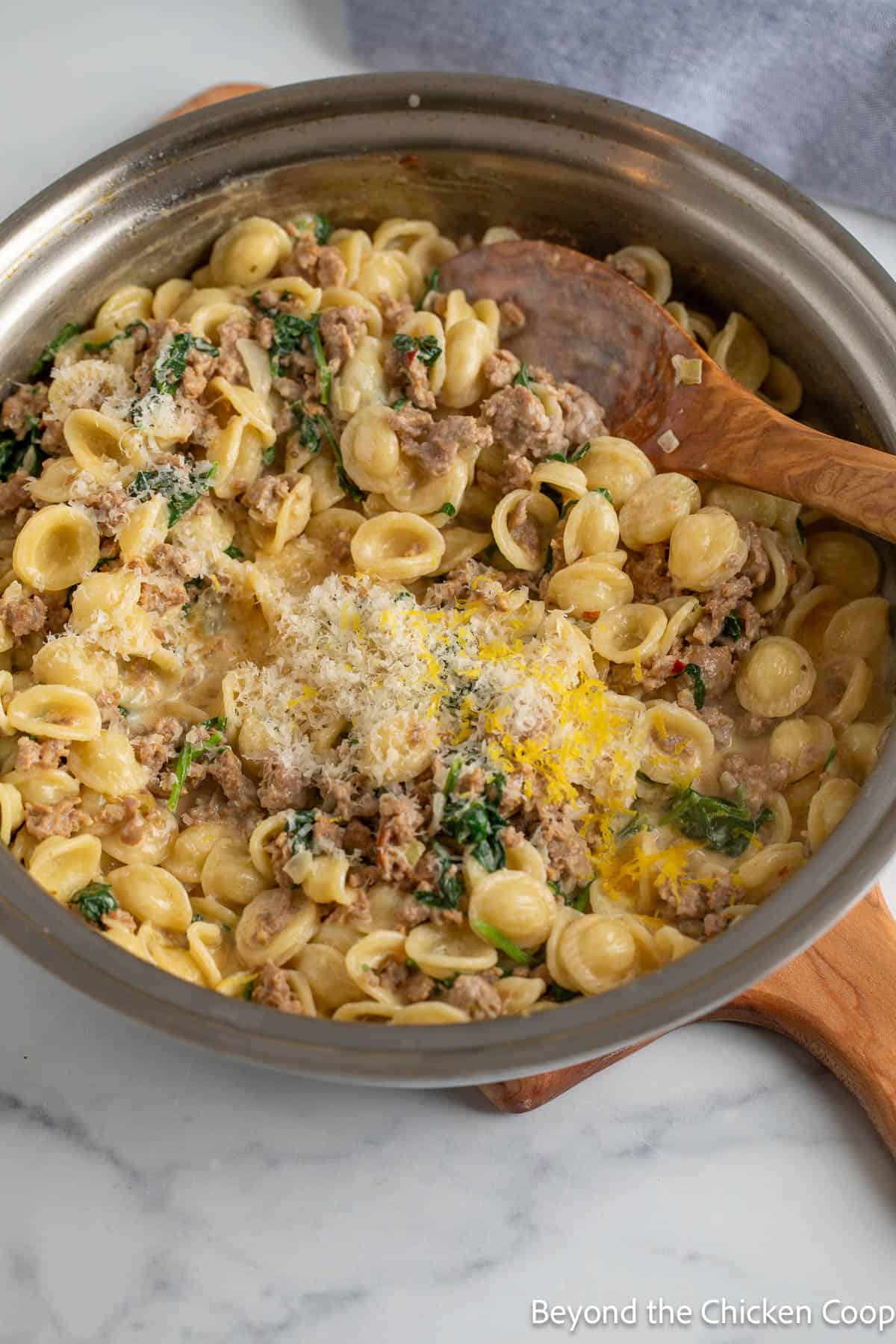 Freshly grated Parmesan cheese on a skillet filled with pasta. 