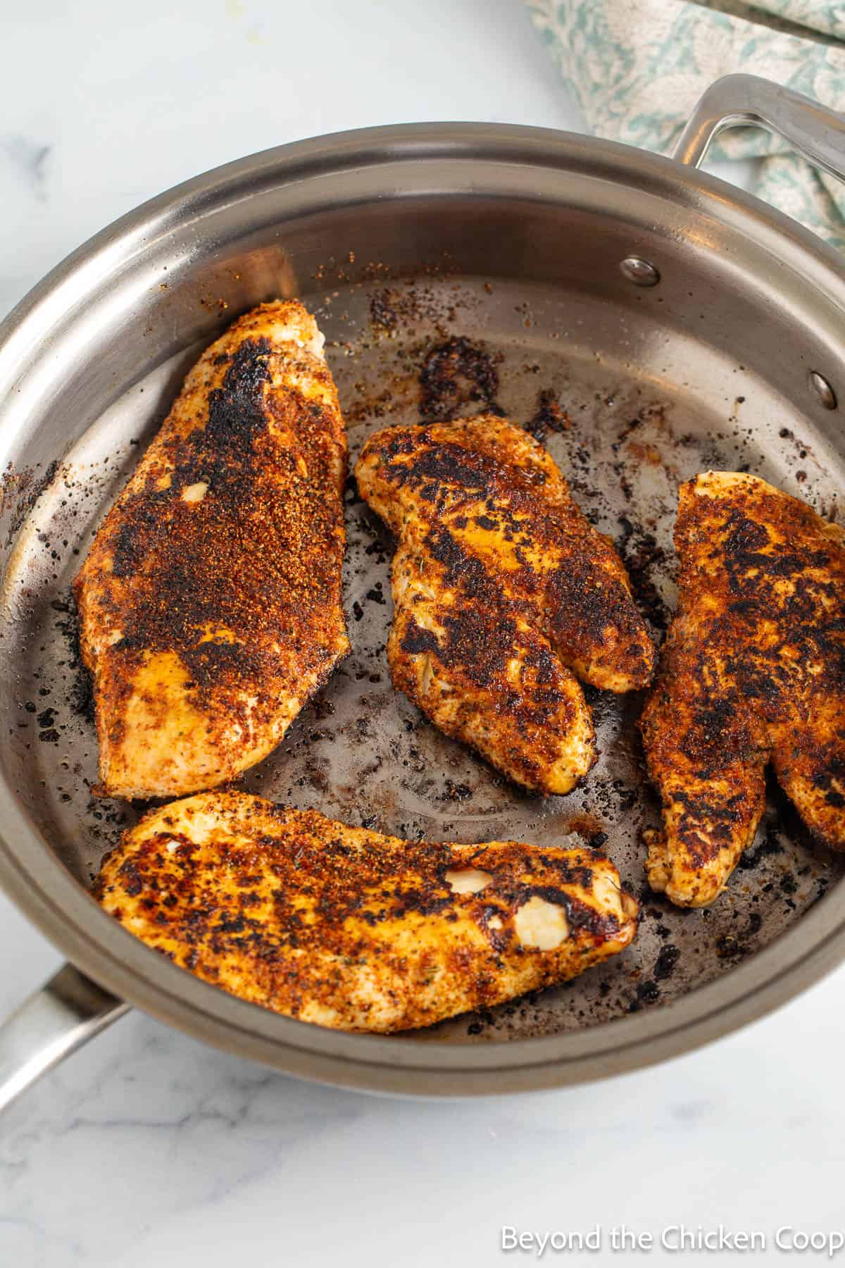 Blackened chicken breasts in a pan. 