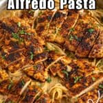 Sliced chicken breasts over fettuccine alfredo in a skillet.