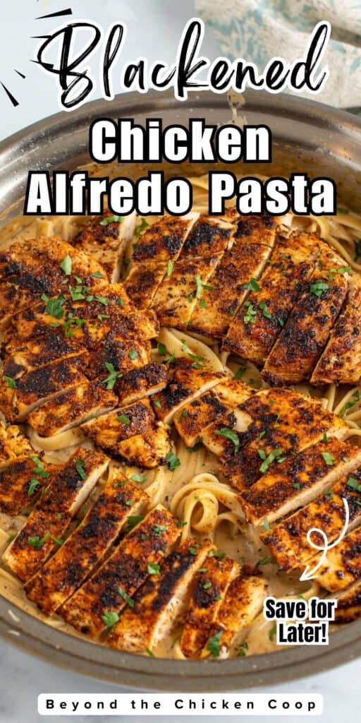 Sliced chicken breasts over fettuccine alfredo in a skillet.