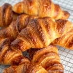 Homemade Croissants stacked on a cooling rack.