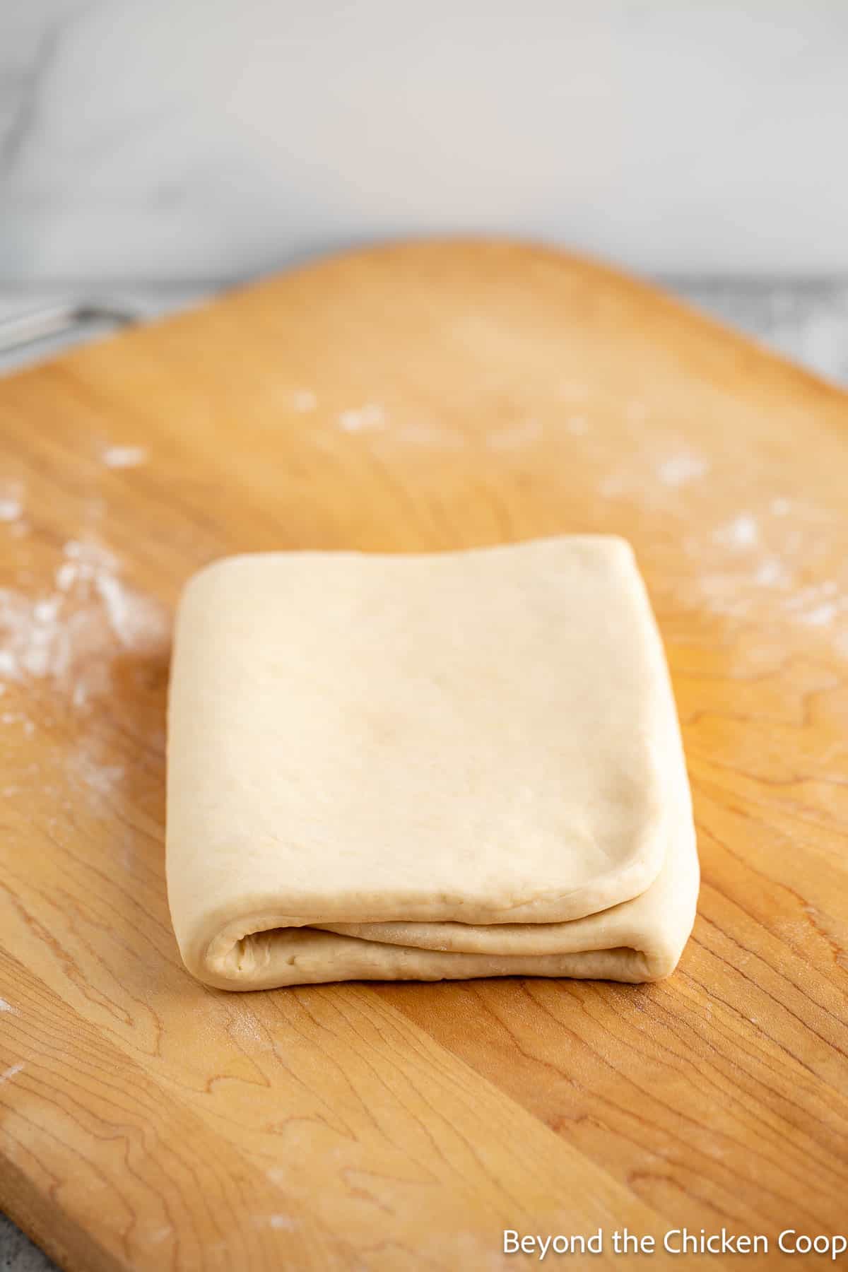 Letter folded puff pastry dough on a wooden board. 