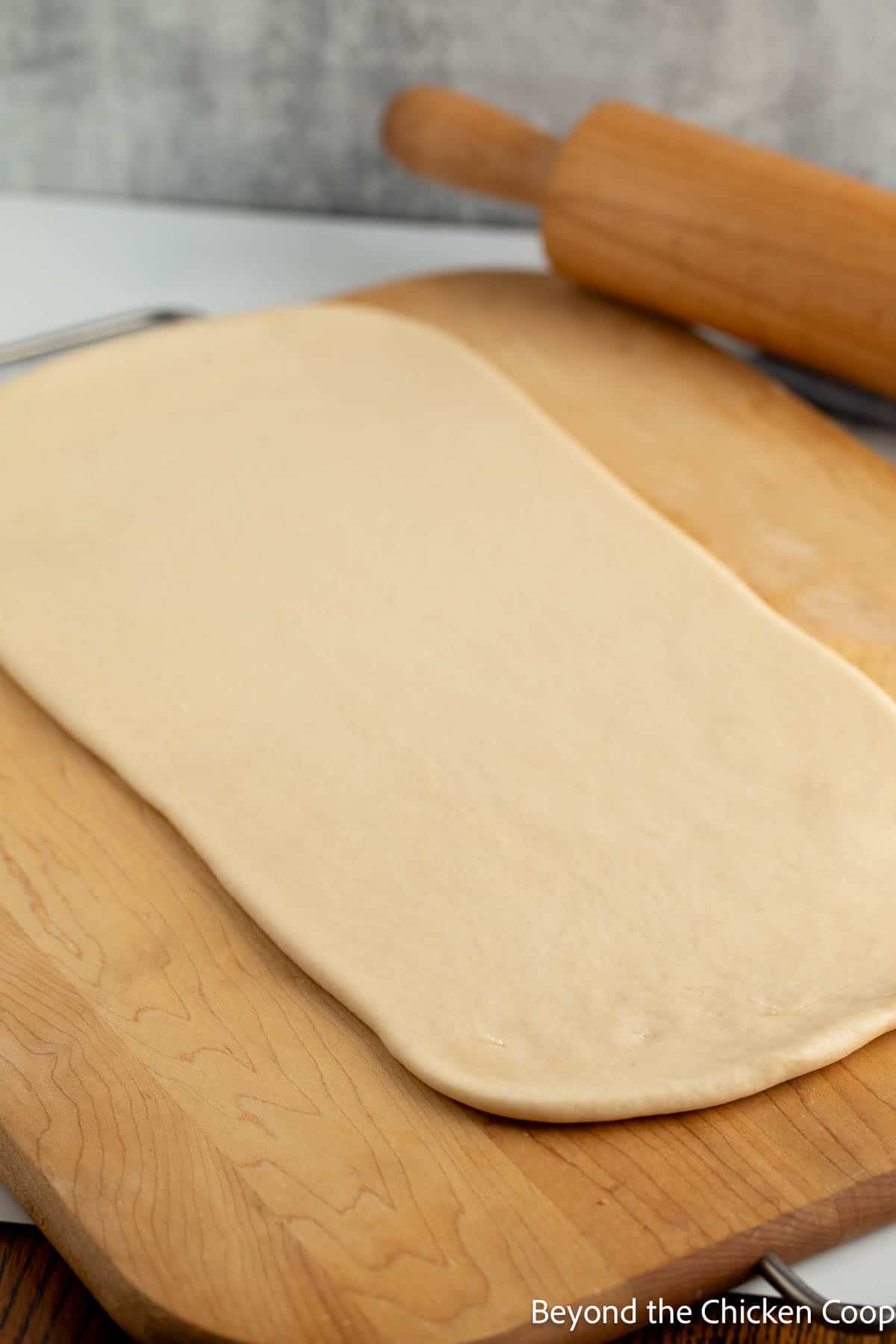 Rolled dough on a wooden board. 