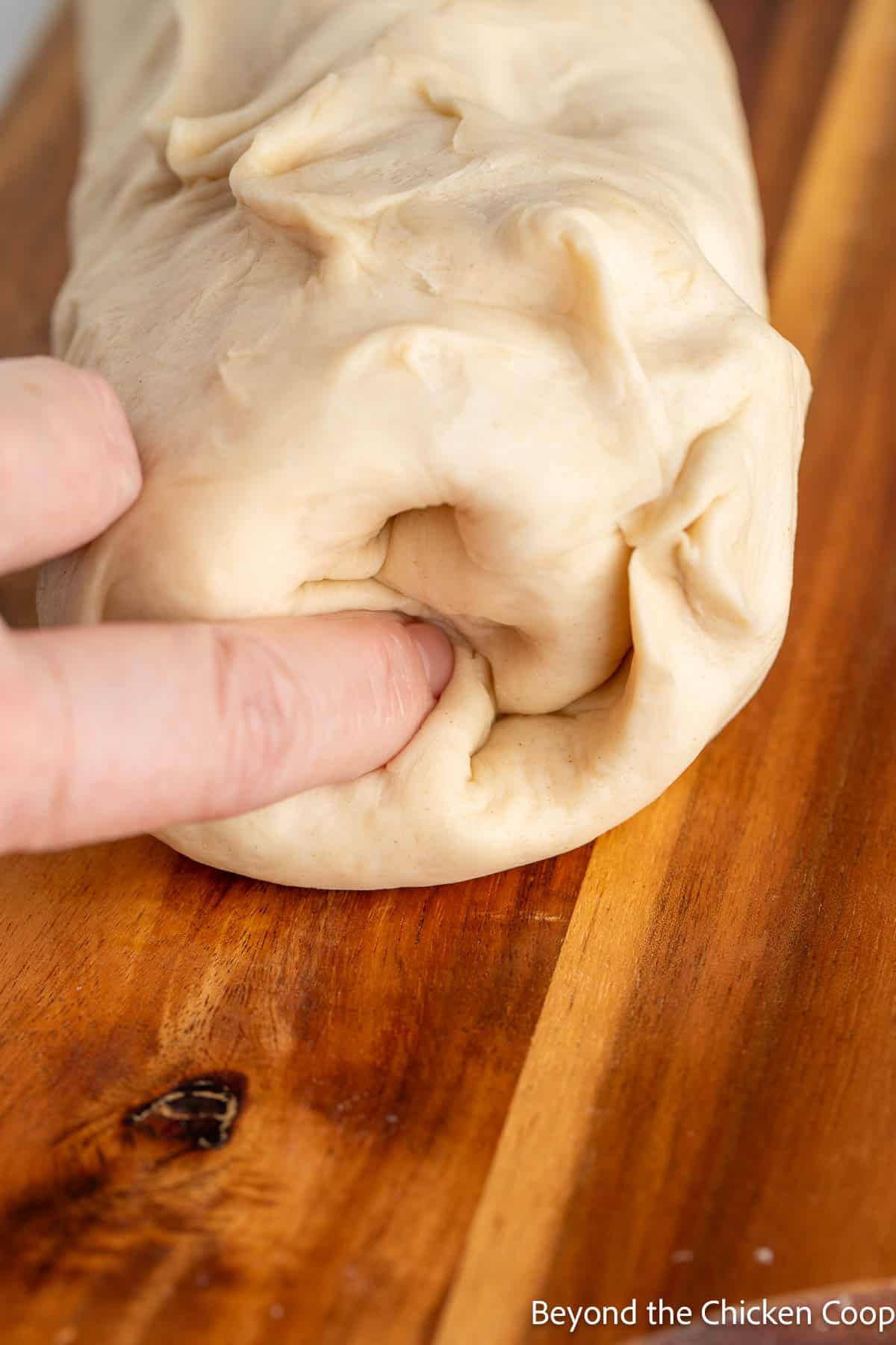 Poking the ends of rolled dough into the center. 