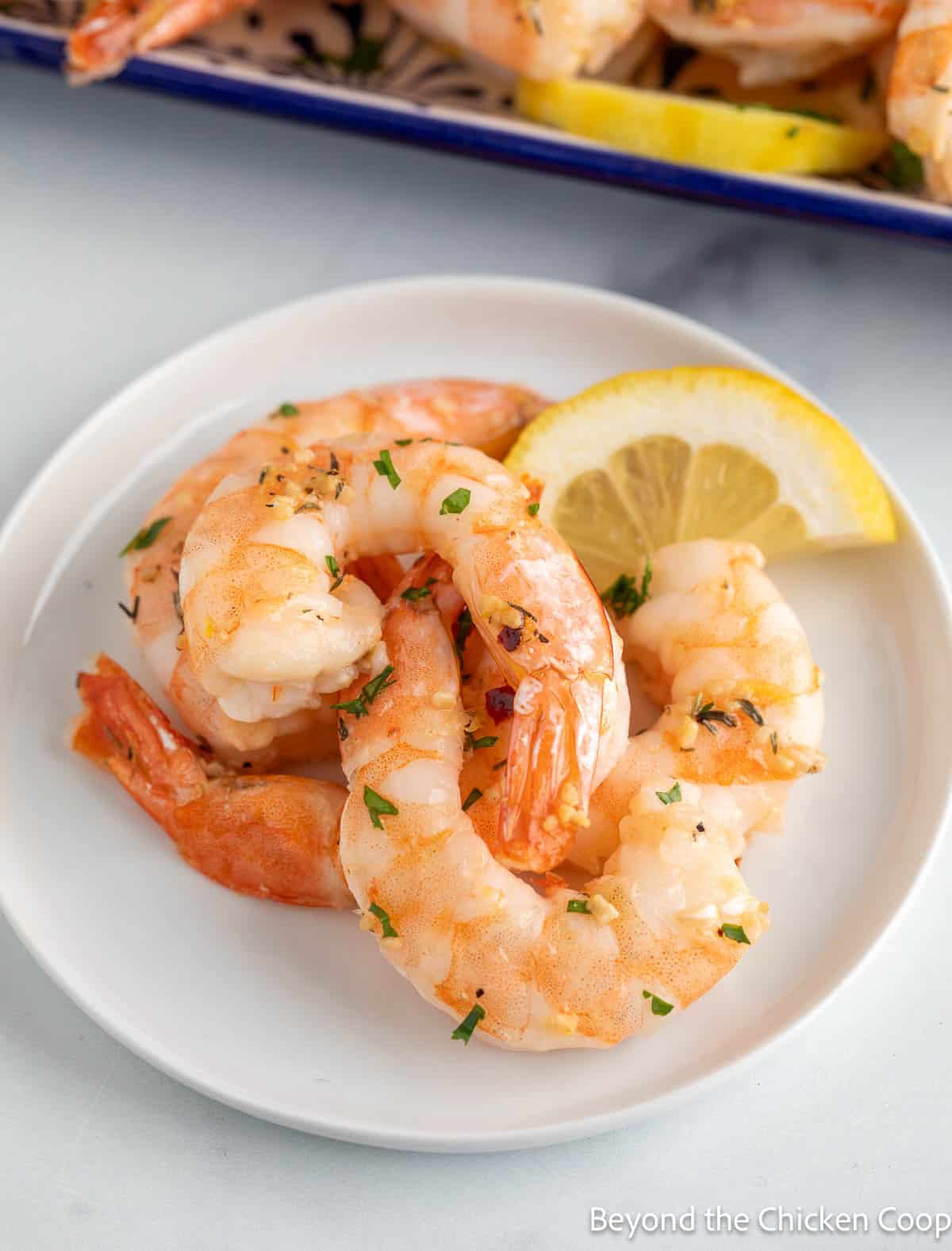 A plate filled with cooked shrimp and a lemon slice. 
