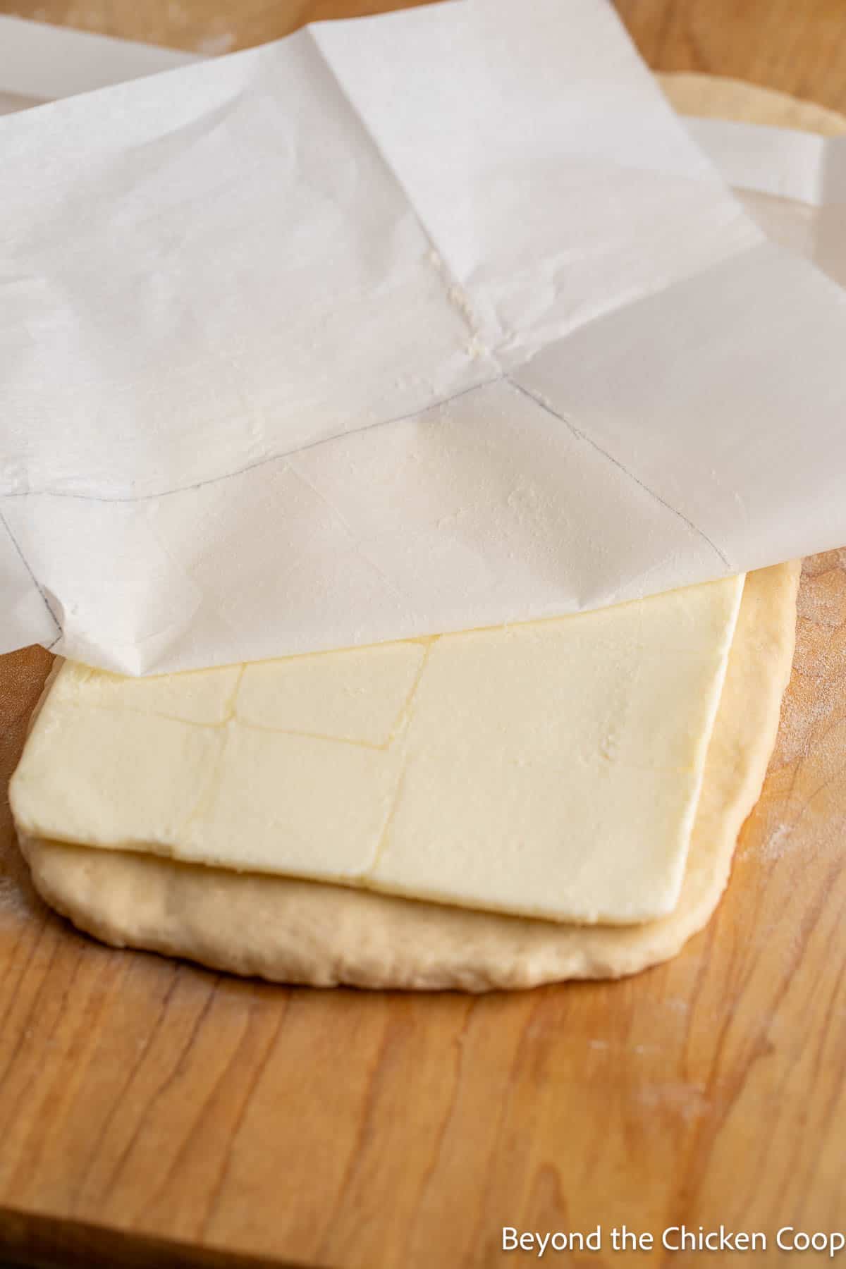Adding butter to croissant dough. 