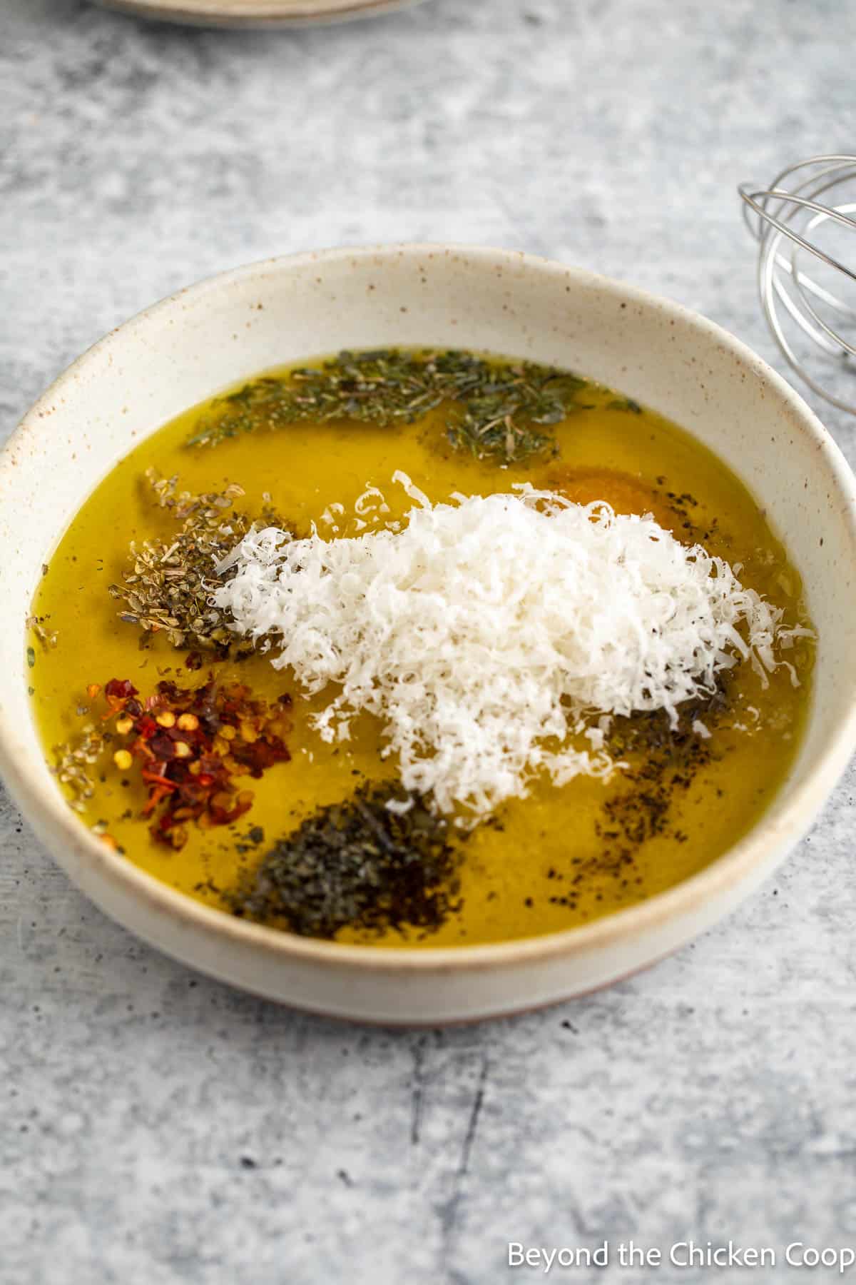 Freshly grated Parmesan in a bowl filled with olive oil and seasonings. 