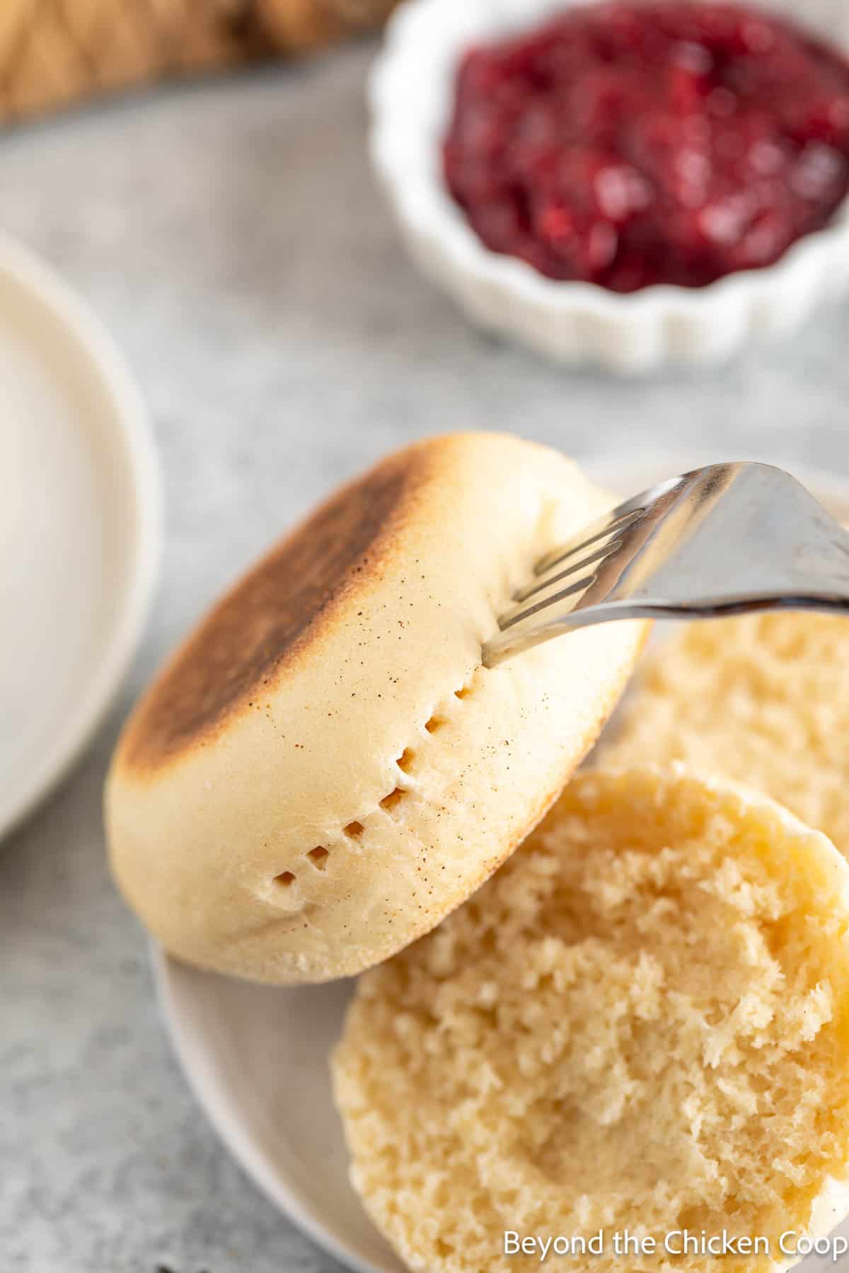 Splitting an English muffin with a fork. 