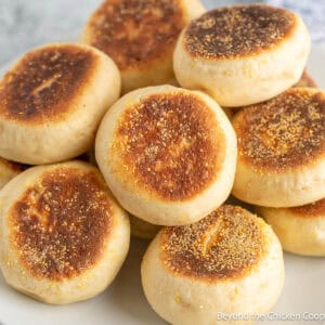 Homemade English Muffins stacked on a white plate.