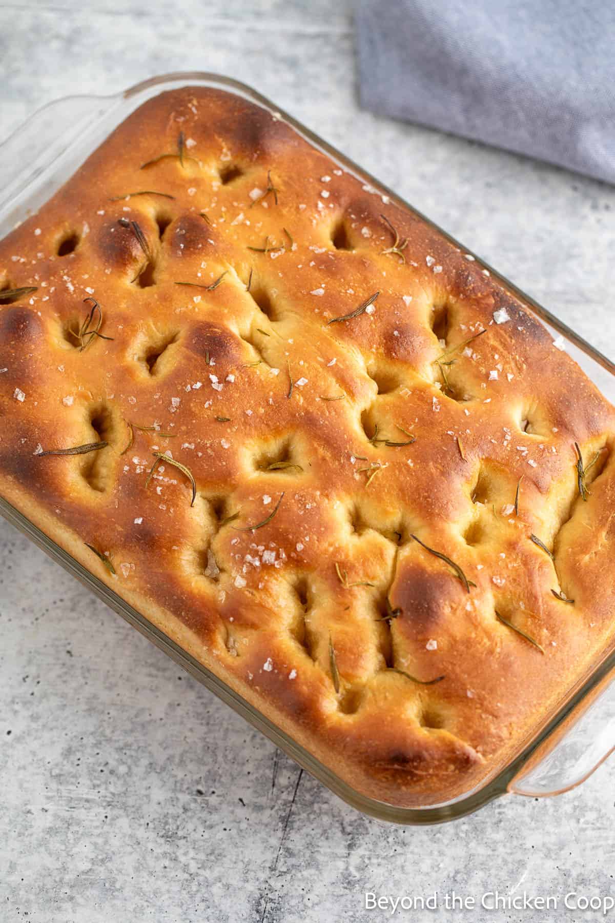Baked focaccia bread in a glass casserole dish. 