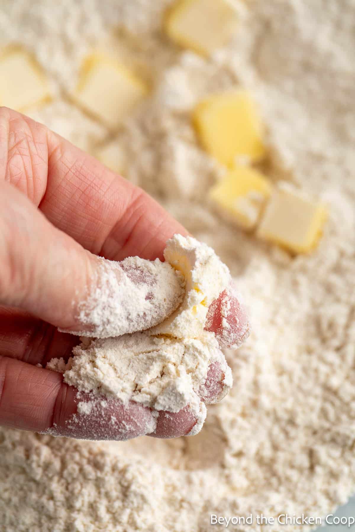 Smashing butter cubes into flour with fingers. 