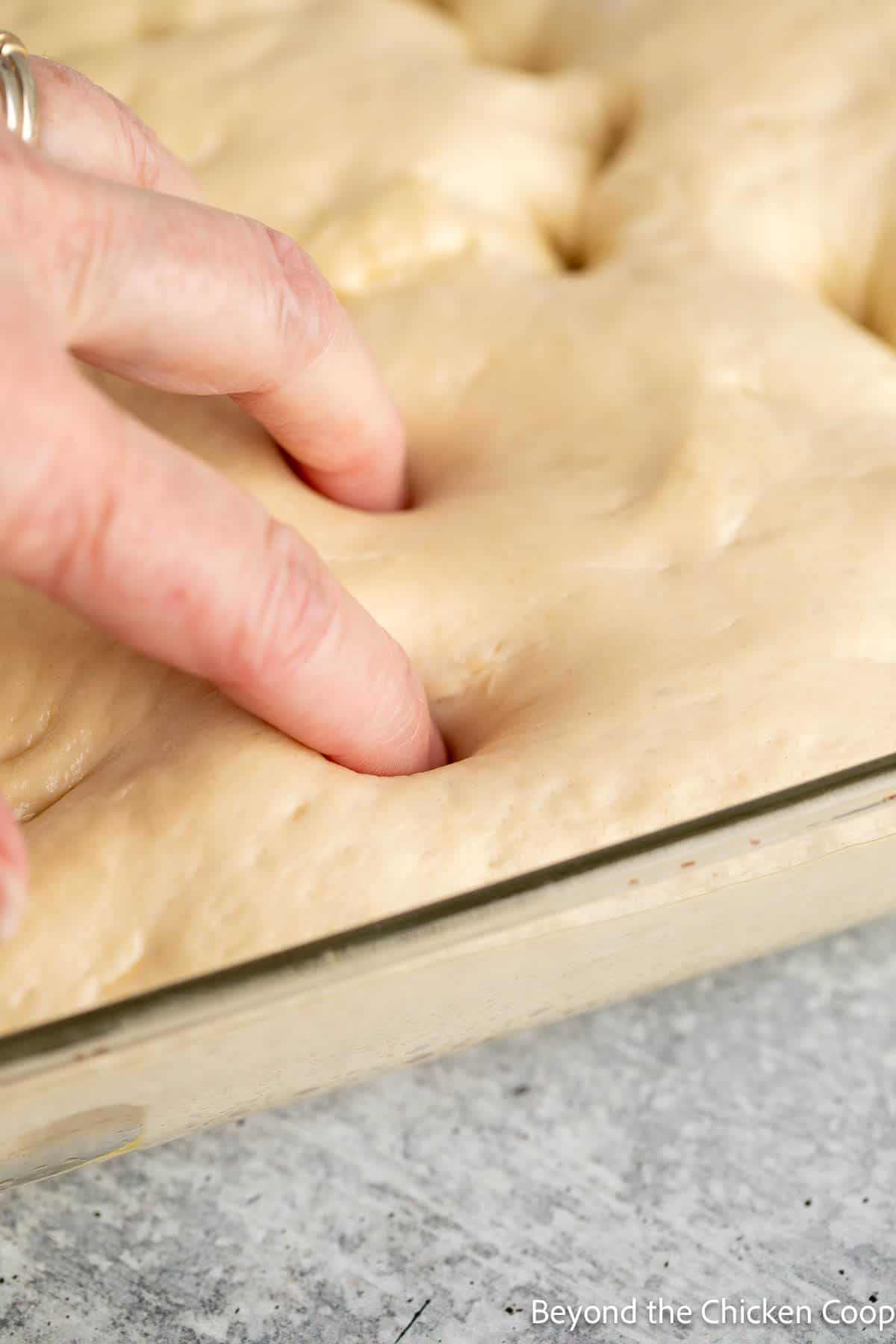 Poking holes into bread dough with fingers. 