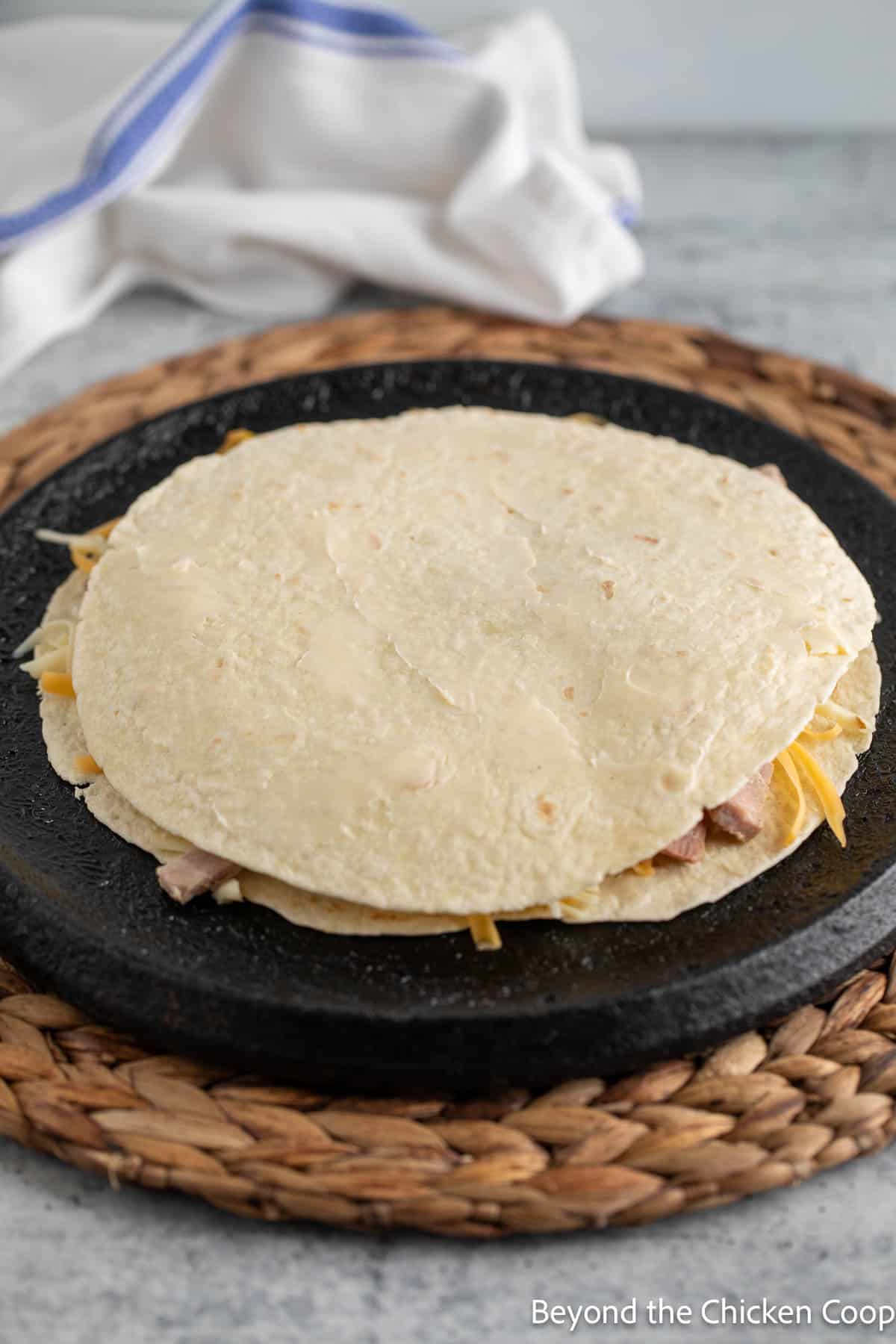 An uncooked quesadilla on a cast iron skillet. 