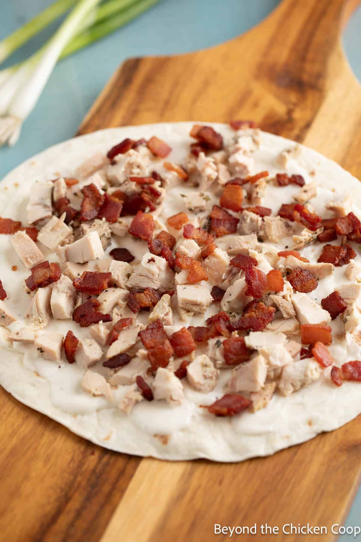 Tortilla topped with chunked chicken and crispy bacon.