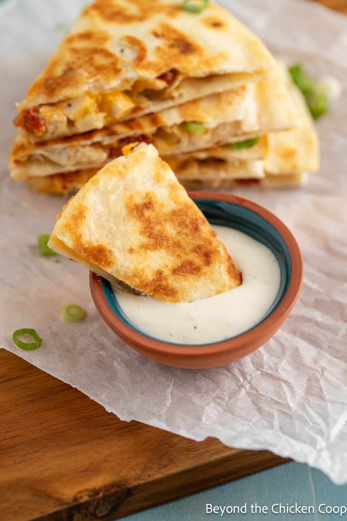 Dipping a wedge of chicken quesadilla into ranch dressing. 