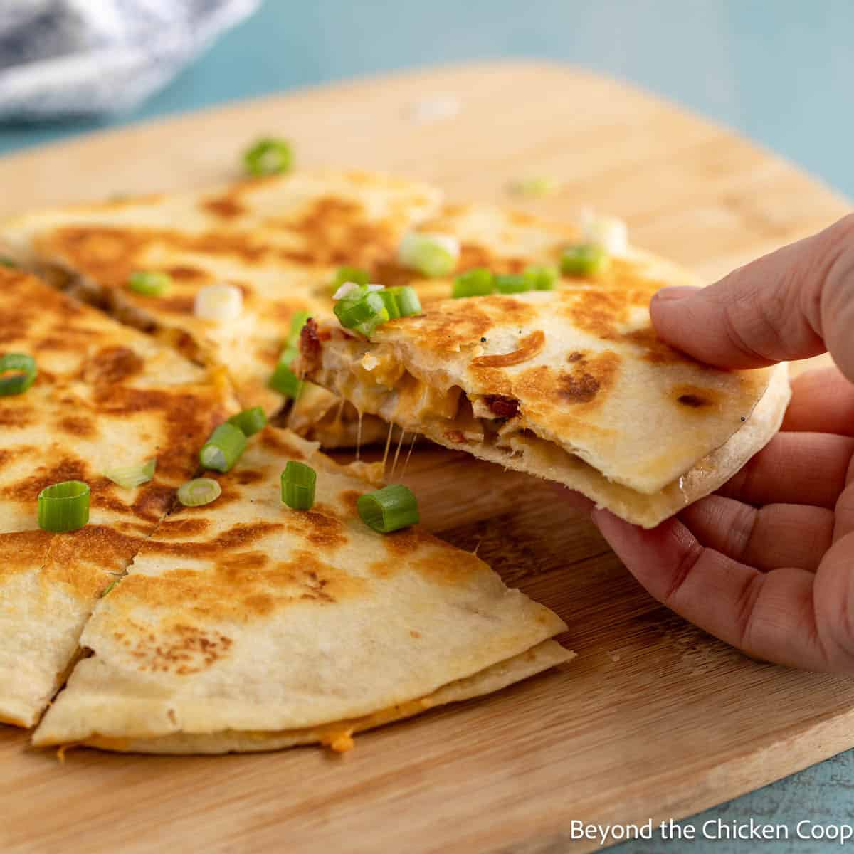 Pulling a wedge of a cheese crisp from the main one. 