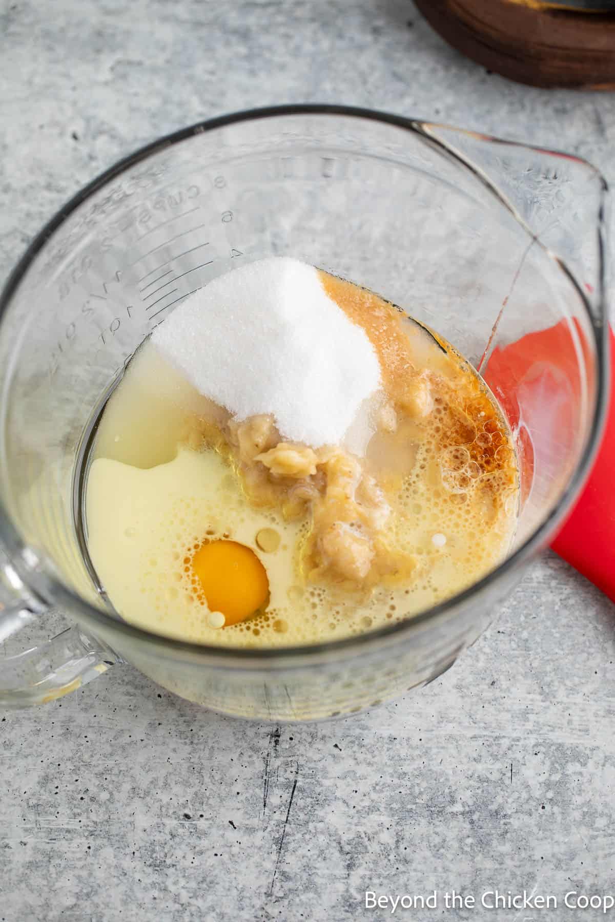 Combining mashed bananas, egg, sugar and vanilla together in a bowl. 