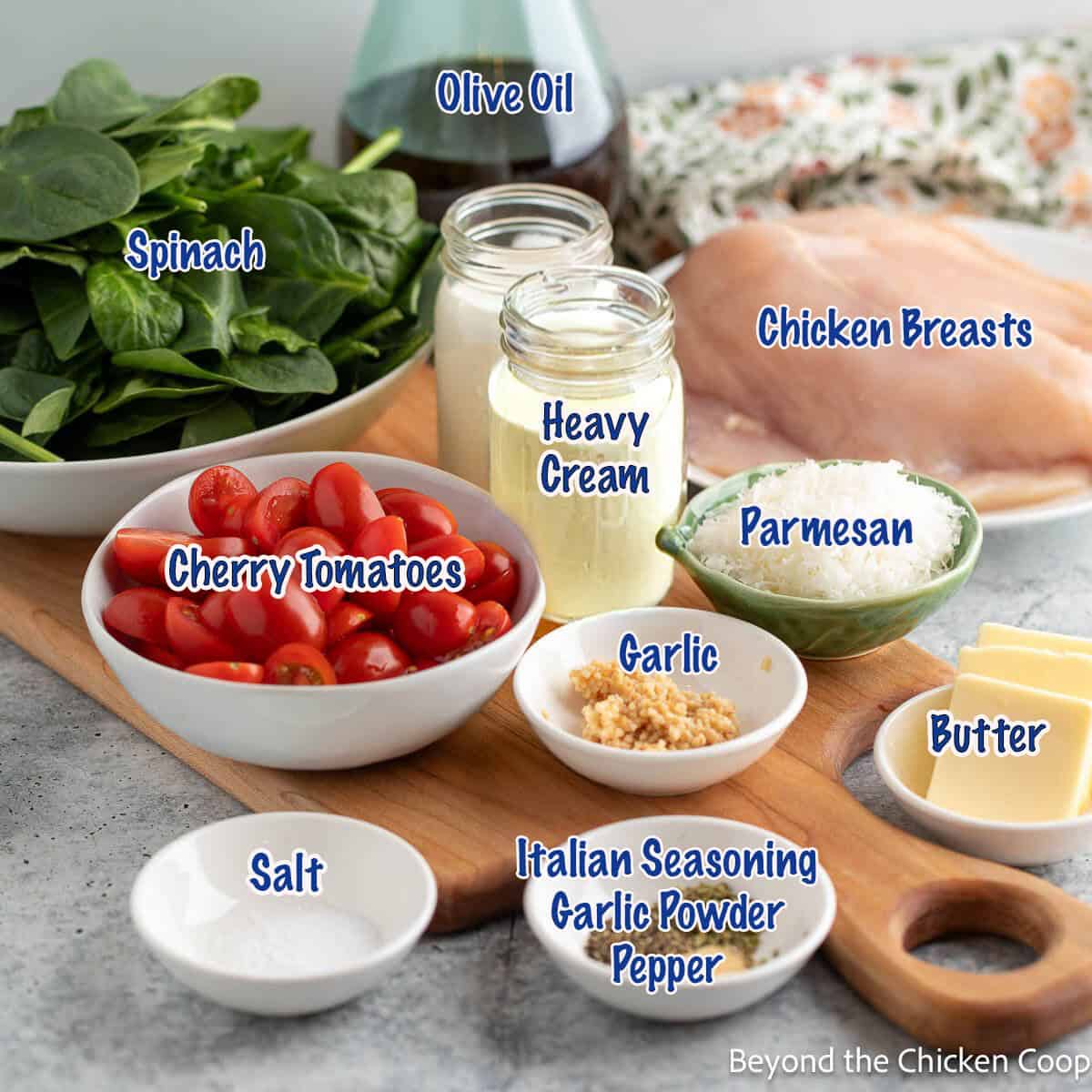 Small bowls filled with ingredients for making a chicken dish with spinach and cherry tomatoes. 