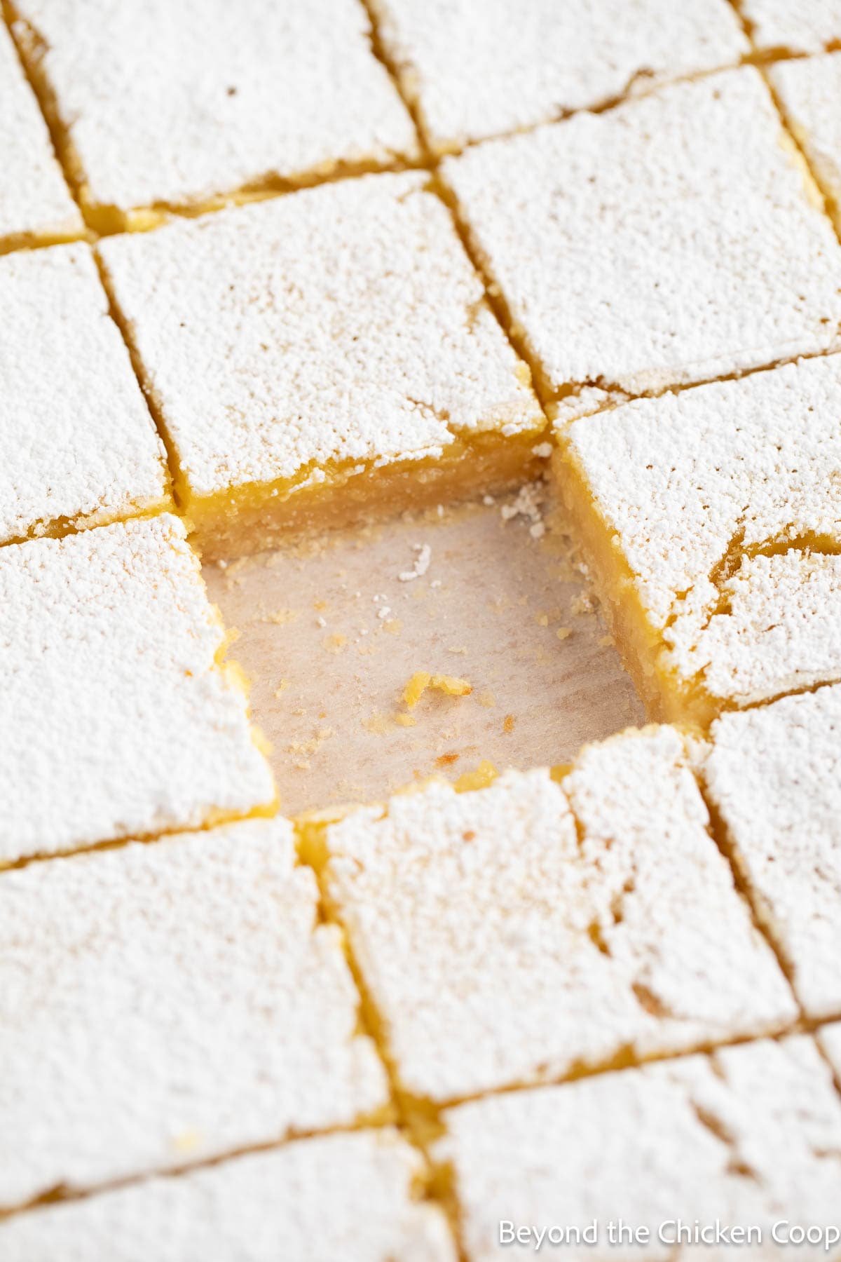 Lemon bars cut into squares with one square missing in the center.