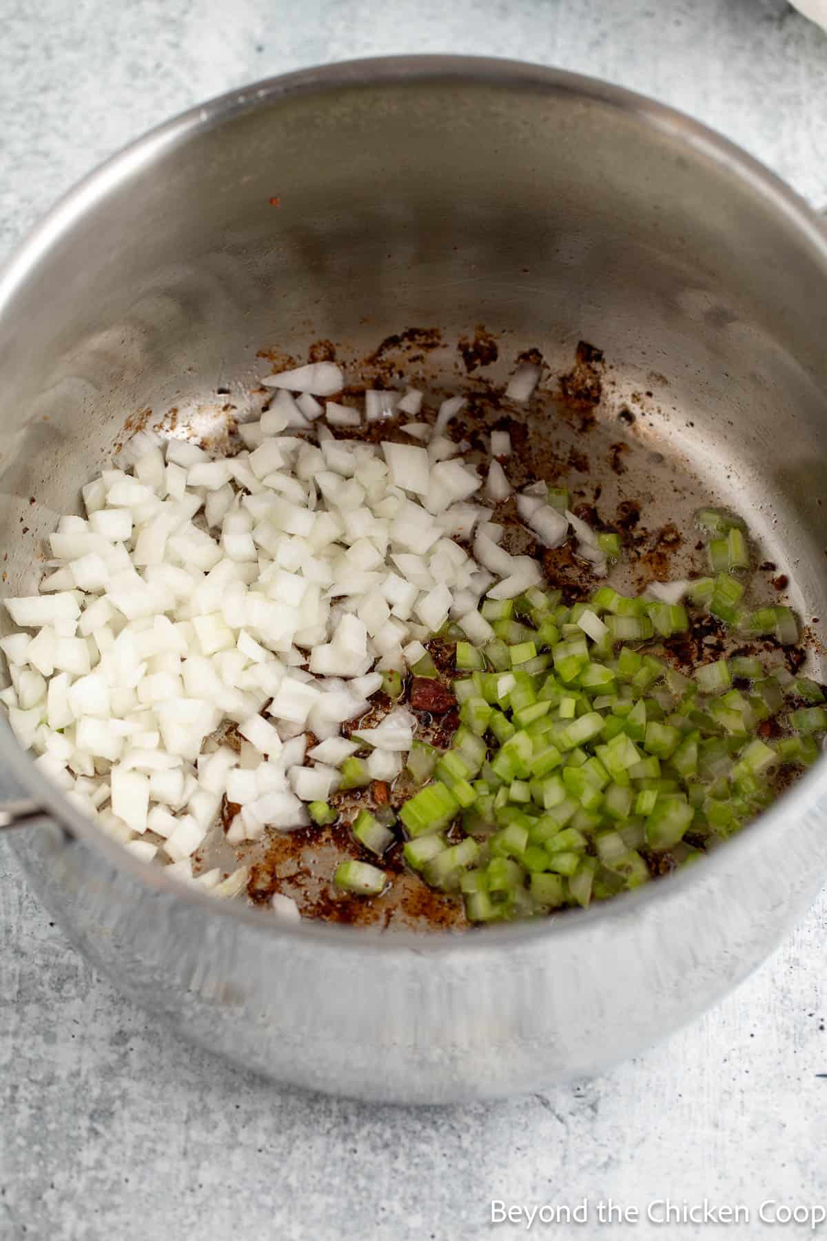 A pot with bacon, onions, and celery.