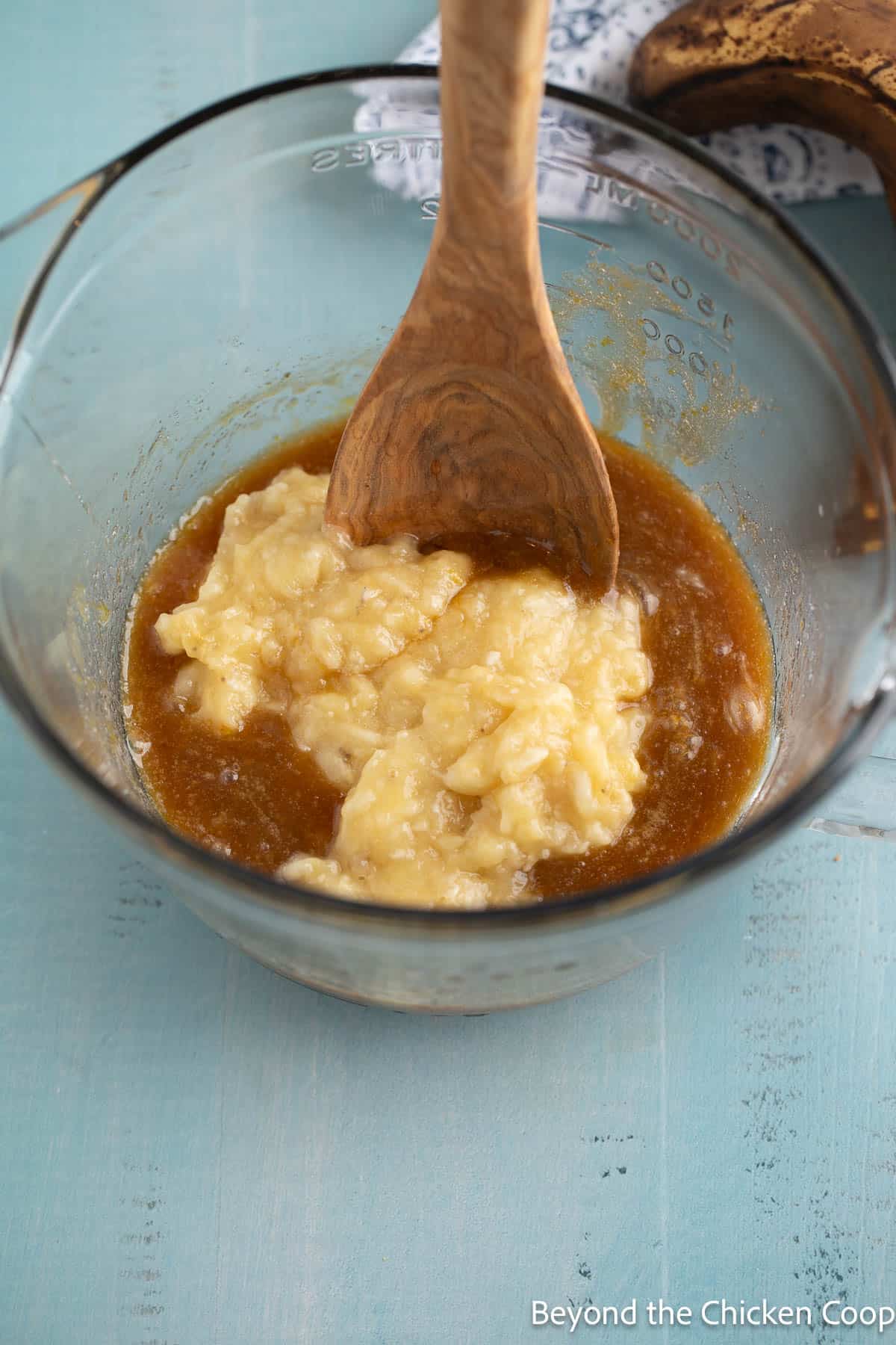 Mashed banana added to a bowl with batter. 