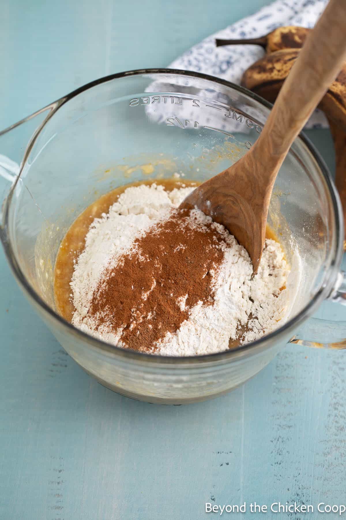 Flour and spices in a glass bowl with a wooden spoon. 