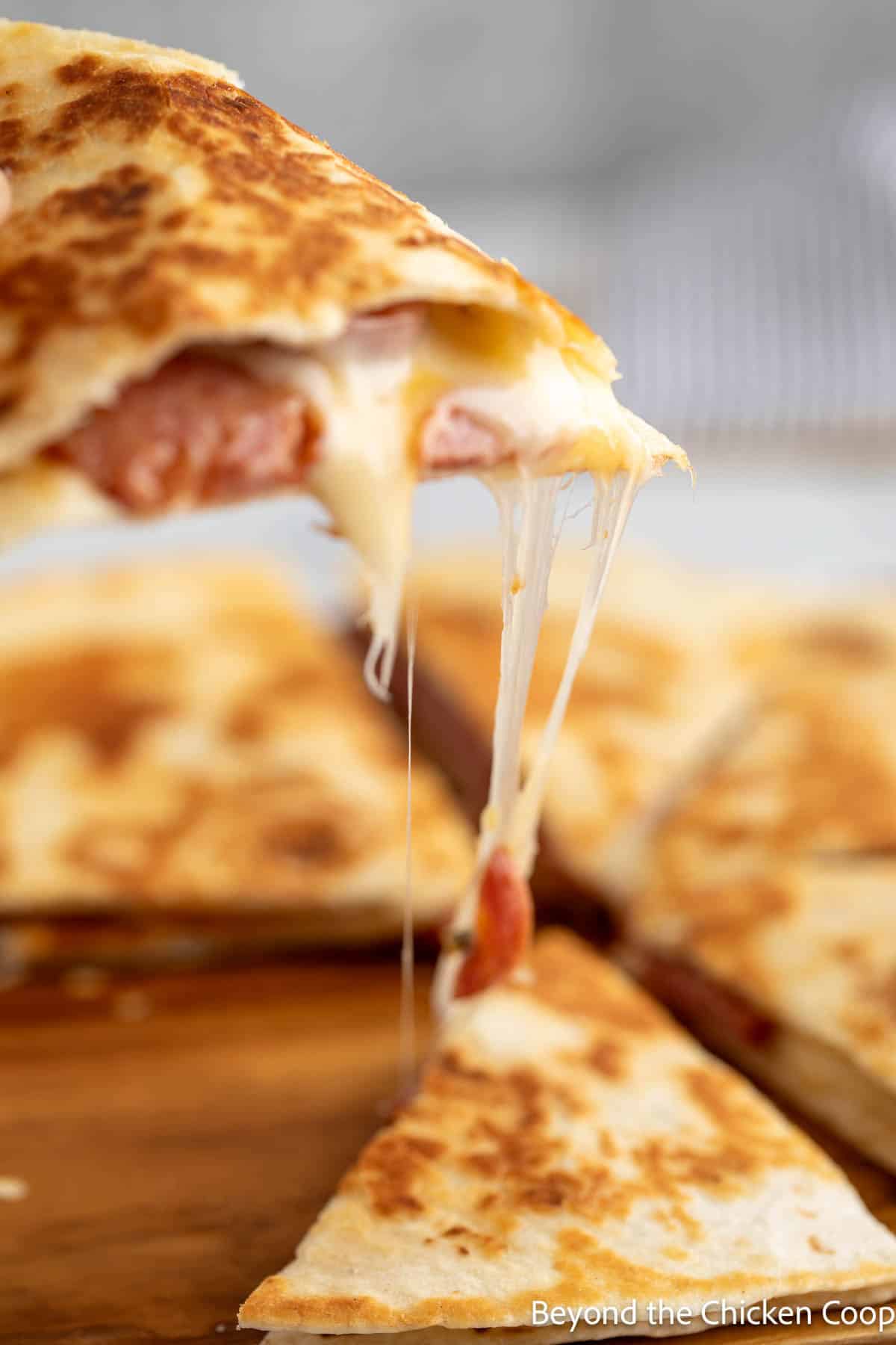 Pulling a wedge of quesadilla up from the rest of the slices. 
