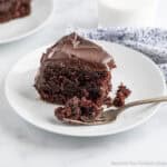 A slice of chocolate layer cake with the end piece sliced off with a fork.